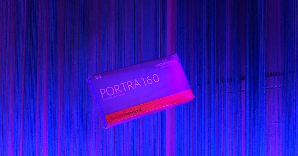 A box of Kodak Professional Portra 160 120 film floats against a background of vertical blue and purple string curtains.