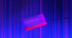 A box of Kodak Professional Portra 160 120 film floats against a background of vertical blue and purple string curtains.