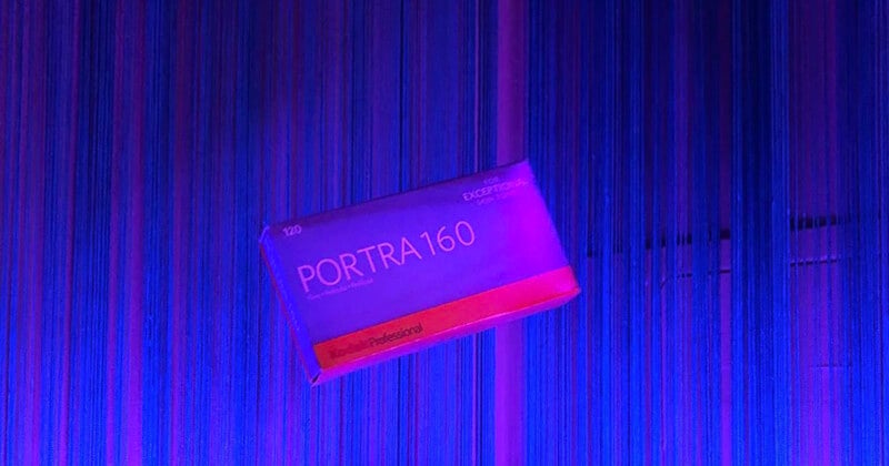 A box of Kodak Professional Portra 160 120 film floats against a background of vertical blue and purple string curtains.