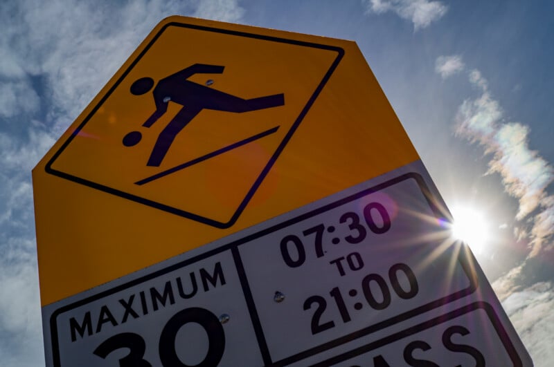 A yellow pentagonal sign showing a person dribbling a basketball, mounted above a sign indicating a 30 km/h speed limit from 07:30 to 21:00.