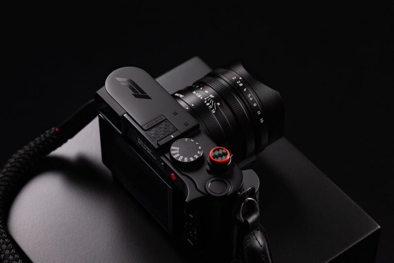A black Leica camera with an F1 logo on the top plate sits on a dark surface, featuring a lens with visible aperture and distance markings.