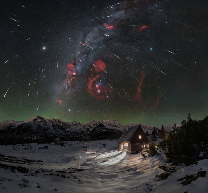A wooden cabin sits in a snowy mountain valley under a night sky filled with a meteor shower and the Milky Way galaxy.