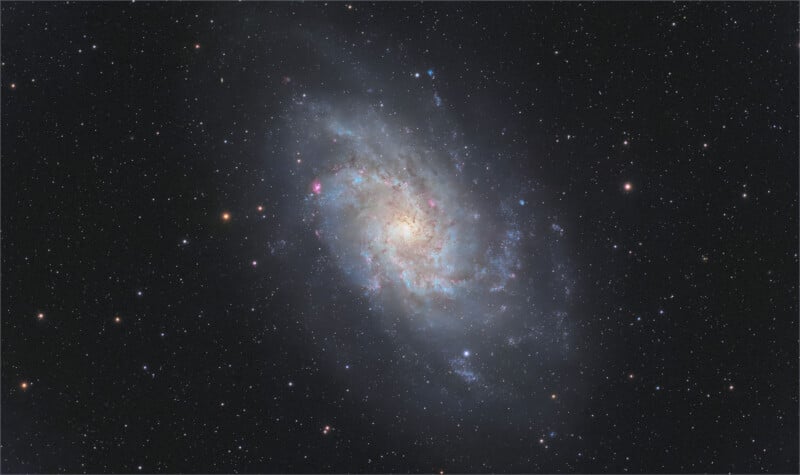 The Triangulum Galaxy, a spiral galaxy with a bright central core and diffuse, star-forming arms, set against a dark starfield.