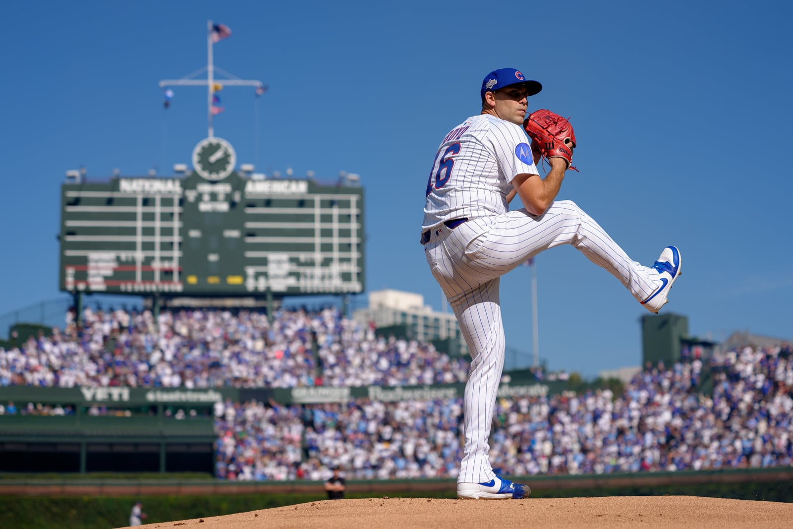 A Chicago Cubs pitcher in a pinstriped uniform stands on the mound with his leg raised, preparing to throw toward the plate.