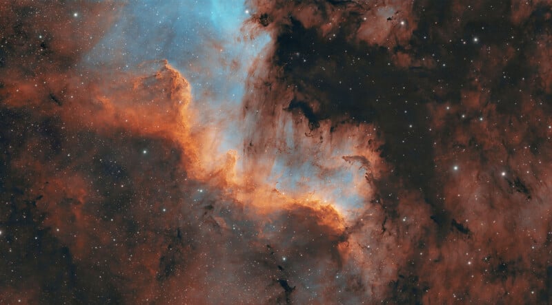 A vibrant nebula featuring glowing orange and blue gas clouds set against a dark, star-filled background.