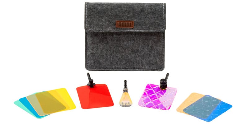 A gray felt carrying case with an "omni" logo sits behind an assortment of colorful photography filters, two clips, and a crystal prism.