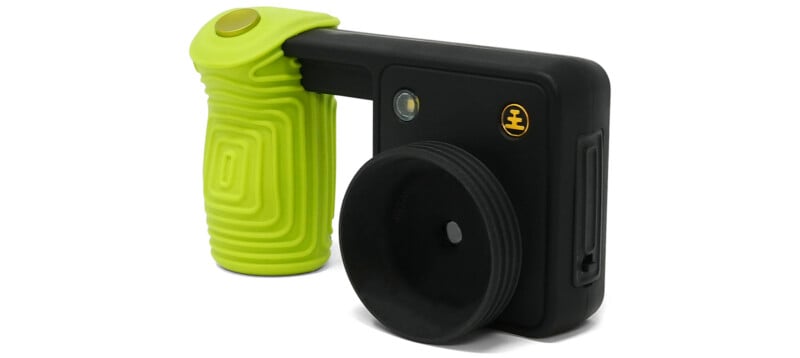 A black rectangular device with a large circular eyepiece and a bright green textured handle attached to its side.