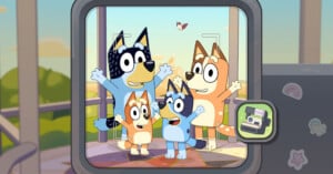 A digital camera screen displays a photo of the Heeler family—Bandit, Chilli, Bingo, and Bluey—posing together outdoors with a bird flying in the background.