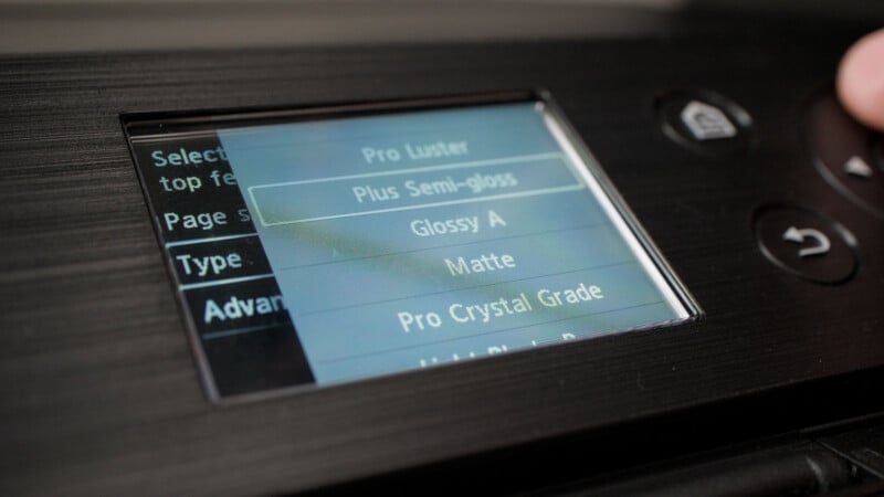 A close-up of a printer's digital menu screen displaying paper type options, with "Plus Semi-gloss" currently highlighted.