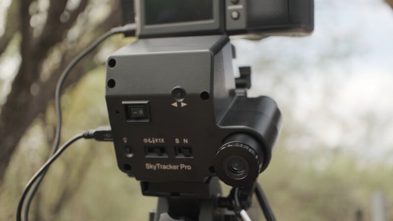 A black iOptron SkyTracker Pro camera mount is attached to a tripod, with a camera mounted on top and a polar scope visible on the side.
