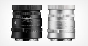 Two Sigma 50mm 1:1.4 CL DG lenses, one in black and one in silver, standing side-by-side against a white background.