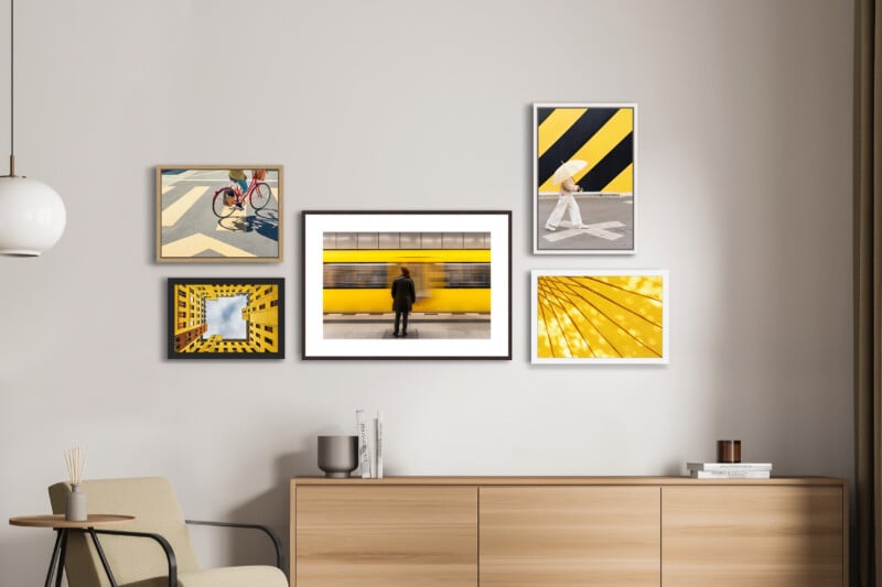 A gallery wall featuring five framed yellow-themed photographs hangs above a wooden sideboard and an armchair in a minimalist room.