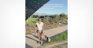 A woman in a white t-shirt and shorts stands on a sidewalk with a small dog on a leash, partially obscured by a polka-dot umbrella, while a group of people stands in the background.