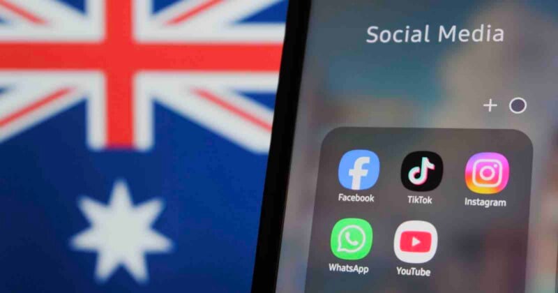 A smartphone screen displays a folder labeled "Social Media" containing icons for Facebook, TikTok, Instagram, WhatsApp, and YouTube, with the Australian flag blurred in the background.