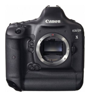 A front view of a black Canon EOS-1D X digital SLR camera body with the lens detached, showing the mirror box and lens mount.