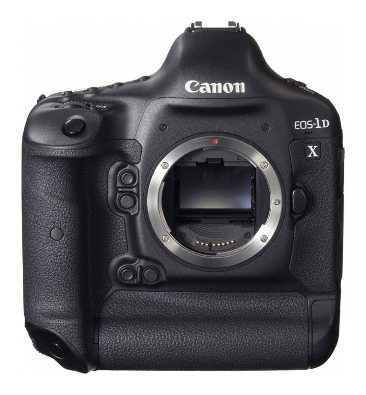 A front view of a black Canon EOS-1D X digital SLR camera body with the lens detached, showing the mirror box and lens mount.