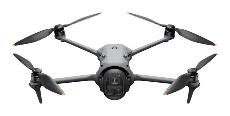 A gray, four-propeller drone is centered against a white background, featuring a front-facing camera module labeled "Hasselblad" and "Mavic 3 Pro" printed on the side arm.
