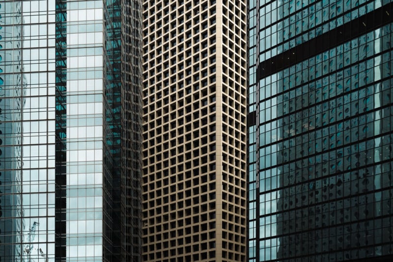 Three adjacent skyscrapers with distinct glass and concrete grid facades fill the frame.
