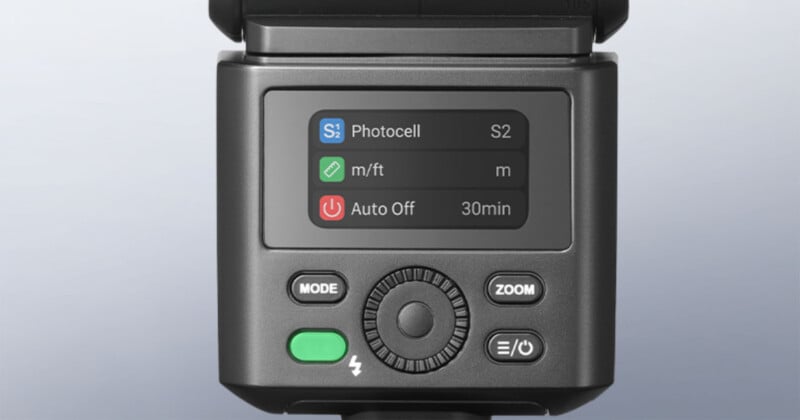 A close-up of a camera flash unit showing a digital menu screen with settings for Photocell S2, distance units in meters, and a 30-minute auto-off timer, along with control buttons and a dial.