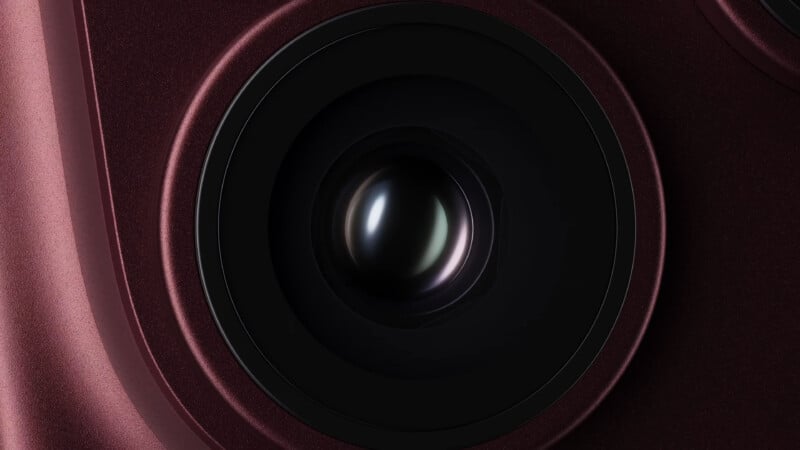 A close-up view of a dark red smartphone camera lens set within a circular housing.