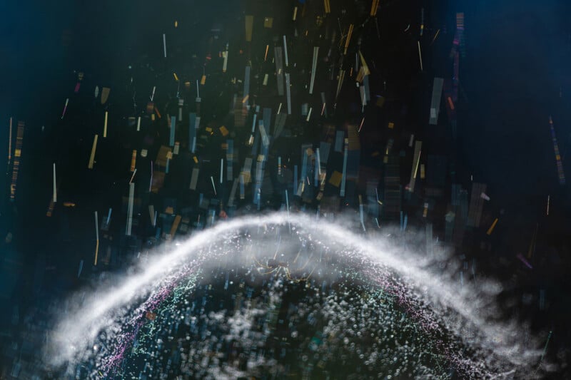 A spider sits at the center of a web illuminated by a bright, curved arc of light against a dark, abstract background.
