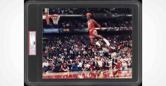 A PSA-authenticated, autographed photograph of Michael Jordan performing a slam dunk during a game, encased in a protective slab.