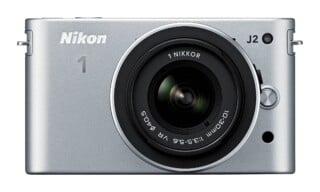 A silver Nikon 1 J2 mirrorless camera with a 1 NIKKOR 10-30mm lens attached, viewed from the front.