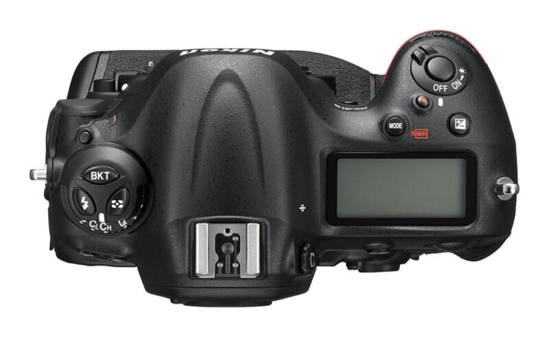 Top view of a black digital SLR camera body showing the shutter button, LCD status screen, hot shoe, and various control buttons.