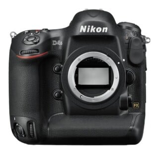 A front view of a black Nikon D4s DSLR camera body with the lens detached, showing the lens mount and mirror.