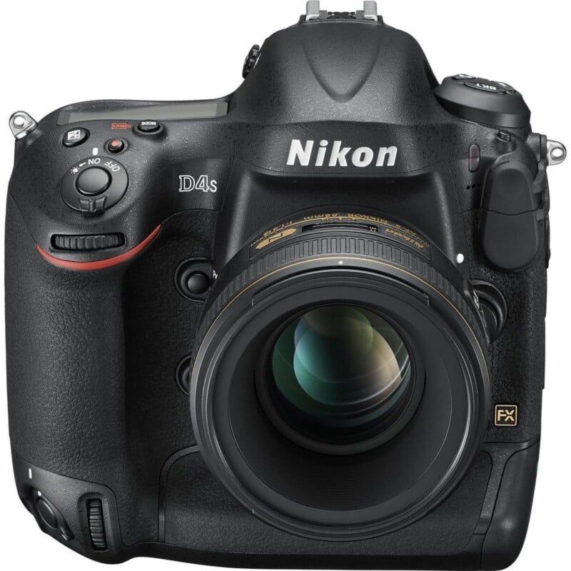 A front-facing Nikon D4s DSLR camera with a lens attached, featuring a black textured body and prominent white branding.