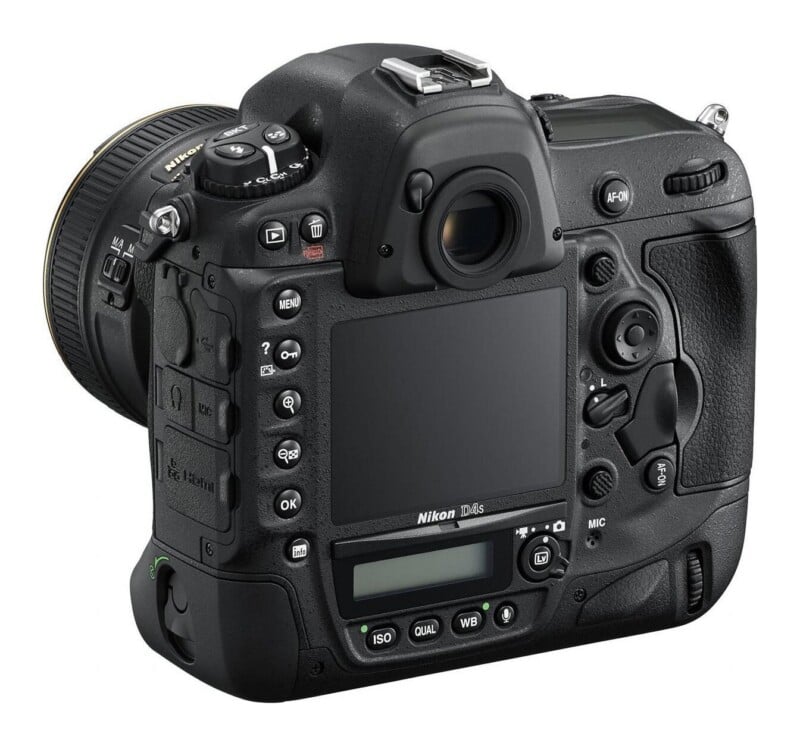 The back view of a black Nikon D4s DSLR camera, showing the LCD screen, viewfinder, various control buttons, and a lens attached on the left.