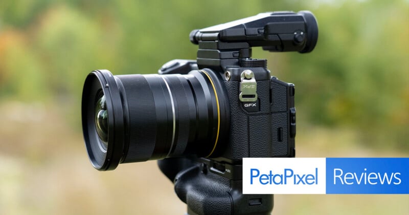 A Fujifilm GFX camera with a wide-angle lens and an electronic viewfinder attached, set against a blurred outdoor background with a PetaPixel Reviews logo in the corner.