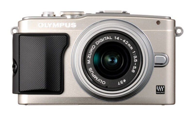 A silver Olympus digital camera with a black grip and an attached M.Zuiko Digital 14-42mm lens, viewed from the front.