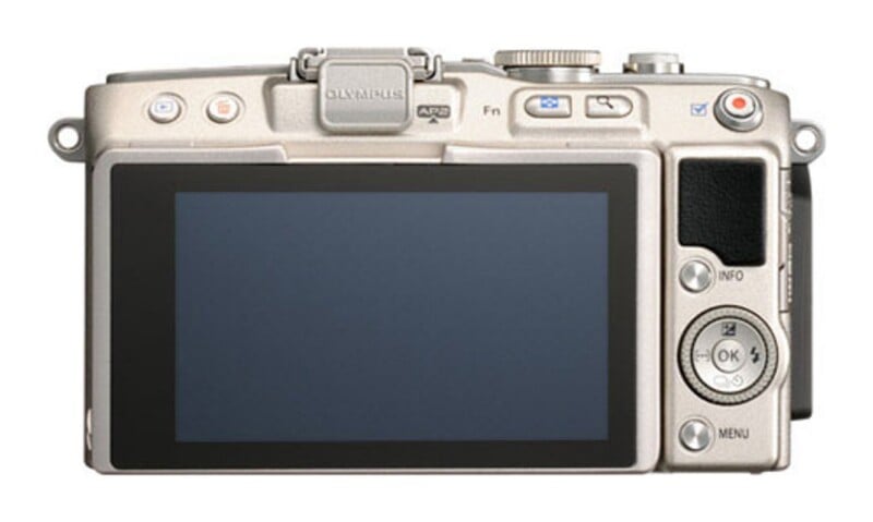 The back of a silver digital camera featuring a large LCD screen, a circular navigation pad with an OK button, and various control buttons including menu, info, and a red record button.