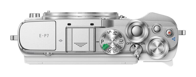 Top-down view of a silver digital camera body showing the mode dial, shutter button, power switch, and control dials.