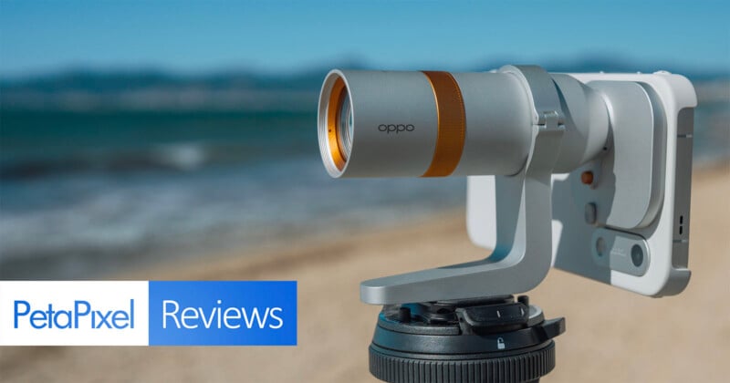 A silver Oppo-branded camera lens attachment mounted to a smartphone on a tripod, with a beach and ocean in the background.