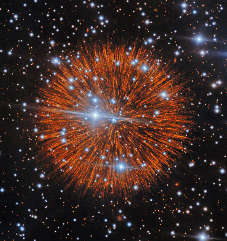 A dense, spherical nebula glows with orange, radial filaments against a dark background filled with scattered white stars.