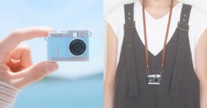 A hand holds a small, light blue Pieni III digital camera on the left, while a person wears a black version of the same camera on a brown strap around their neck on the right.