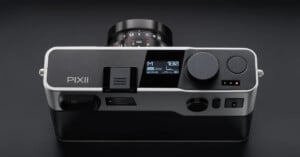 Top-down view of a silver and black Pixii digital rangefinder camera with a lens attached, showing a digital status display on the top plate.