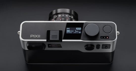 Top-down view of a silver and black Pixii digital rangefinder camera with a lens attached, showing a digital status display on the top plate.