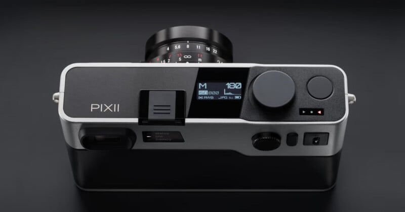 Top-down view of a silver and black Pixii digital rangefinder camera with a lens attached, showing a digital status display on the top plate.