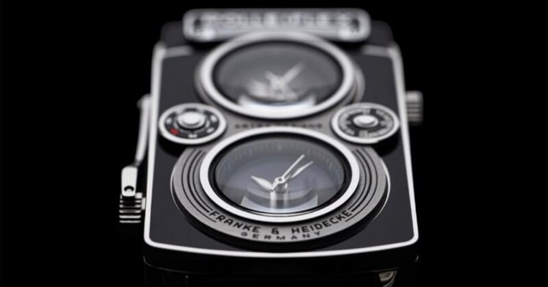 A close-up of a black and silver watch designed to resemble a vintage twin-lens reflex camera, featuring two circular clock faces and the text "FRANKE & HEIDECKE GERMANY" on the lower lens area.