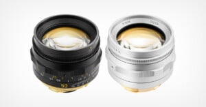 Two manual focus camera lenses, one black and one silver, are positioned side-by-side against a plain white background.
