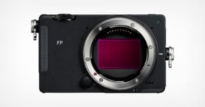 Front view of a black, box-shaped digital camera body with a large circular lens mount and an exposed rectangular sensor, featuring the text "FP" on the front panel.