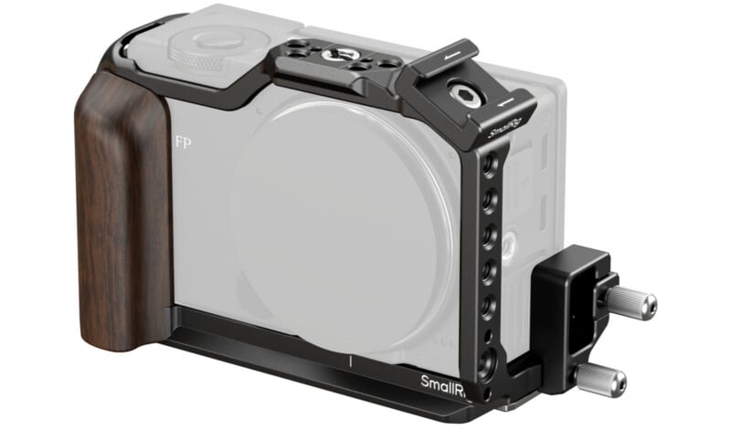 A black metal camera cage with a wooden handgrip attached to a camera body, featuring multiple mounting points and two silver adjustment knobs on the side.